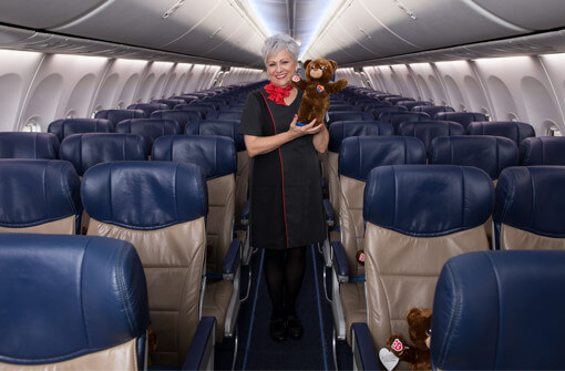 Southwest flight attendant holding a co-branded Southwest Airlines and Build-a-Bear teddy bear.