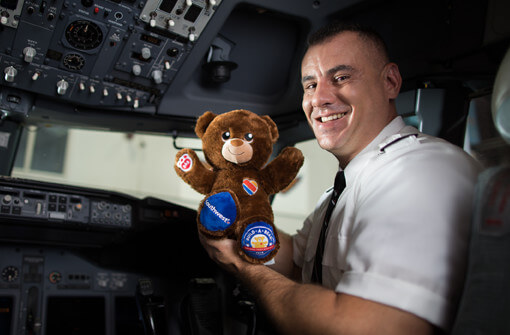 Southwest Pilot in cockpit holding a co-branded Southwest Airlines and Build-a-Bear teddy bear for National Teddy Bear day.