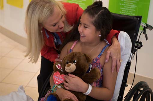 Southwest flight attendant with child at the Ronald McDonald House holding a co-branded Southwest Airlines and Build-a-Bear teddy bear.
