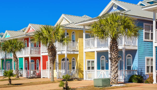 Colorful seaside beach houses with palm trees between each one.