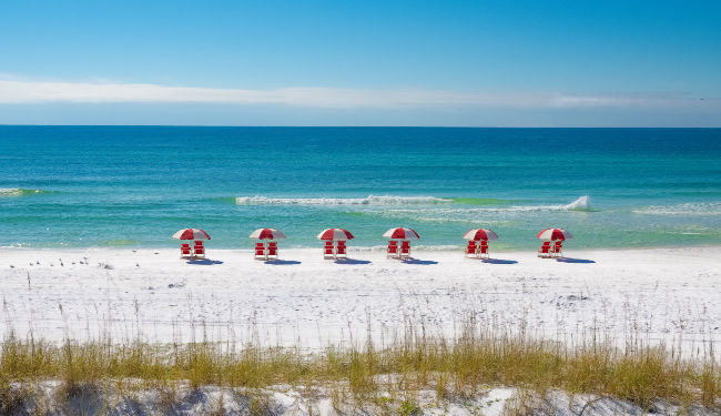 Looking out towards the white sand beach and ocean with umbrellas in the sand.