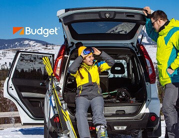 A couple on a skiing trip sitting in the back of a SUV in snow weather